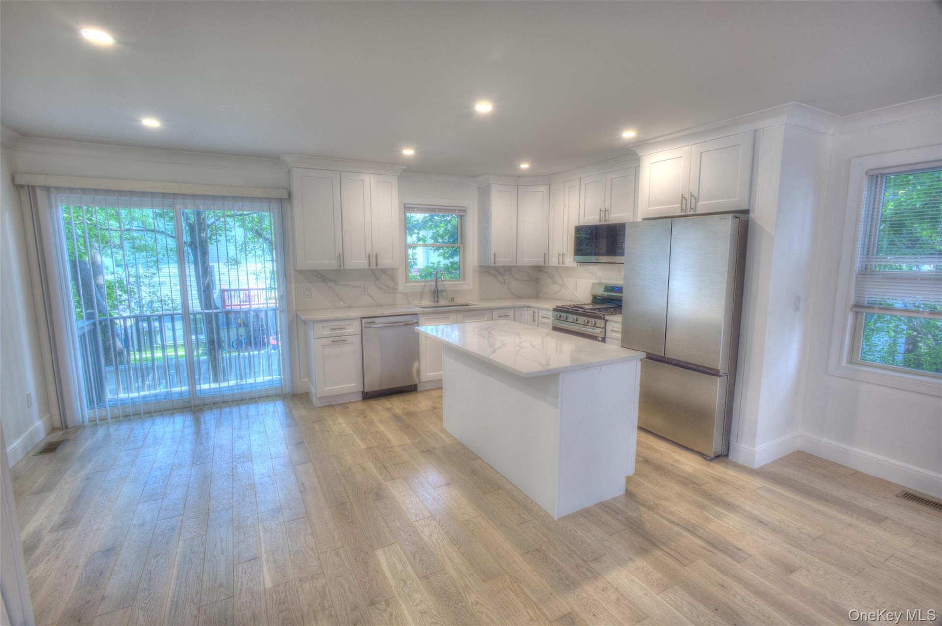 Kitchen featuring shaker-style cabinetry, a central island with a stone-finish countertop, stainless steel appliances, and wood-finish flooring