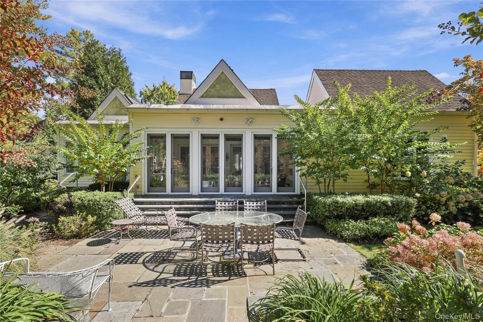 Rear exterior featuring horizontal lap siding, a flagstone patio, multi-panel glass doors, and dual gable roof lines