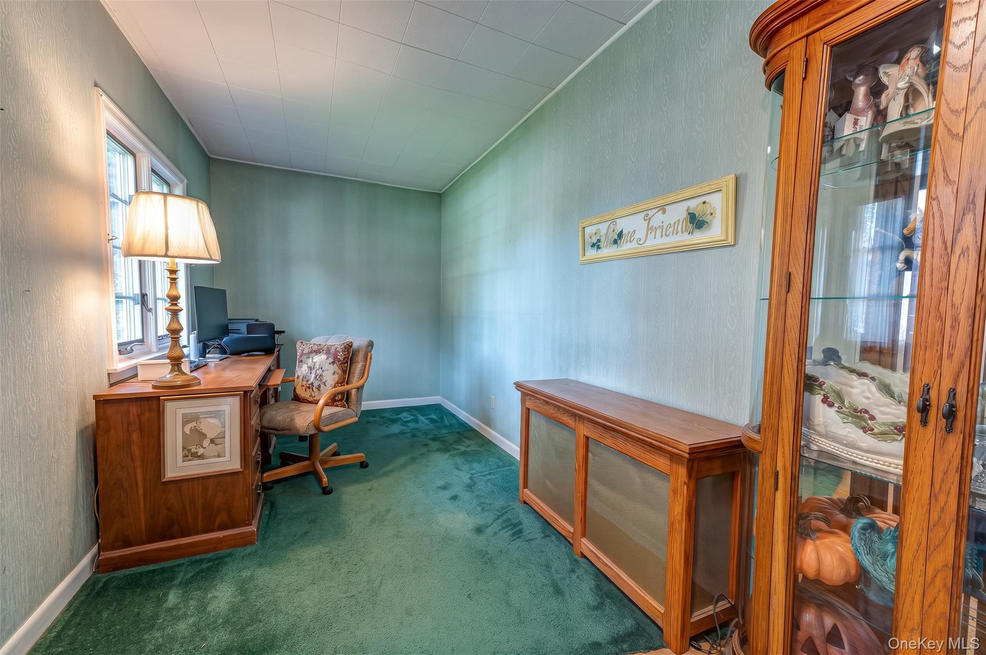 Interior space to left of front entry door featuring a multi-pane window, wall-to-wall carpeting currently used for a home office or could be a nice s