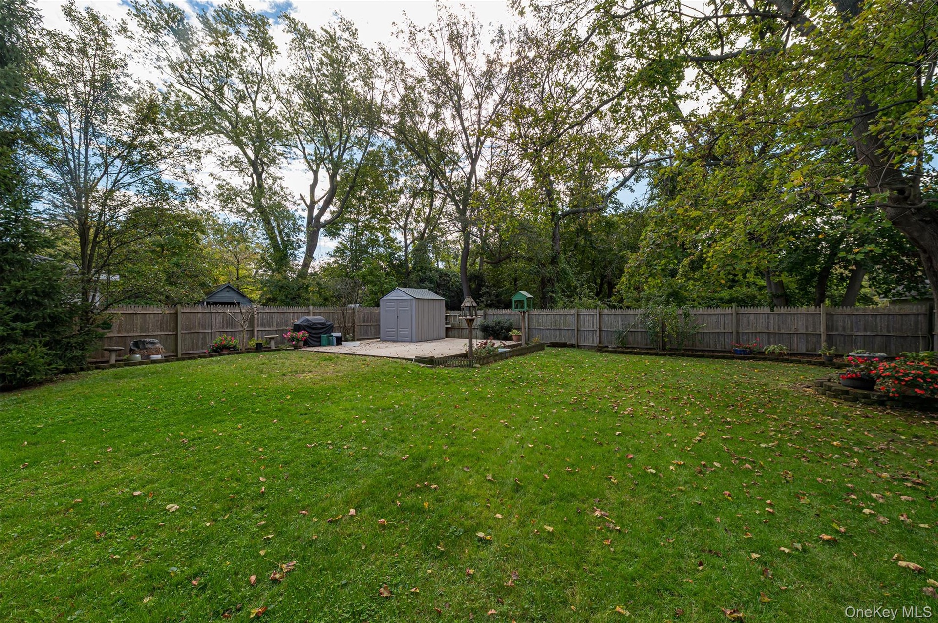 Expansive backyard featuring a level lawn, mature trees, wood privacy fencing, a cement patio area large enough to accommodate a 2 car garage and buil