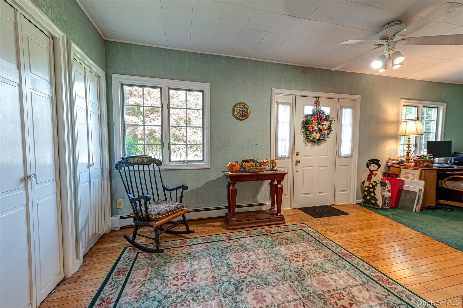 Entrance foyer/sitting area with large windows for plenty of natural light, closets and wood floors.