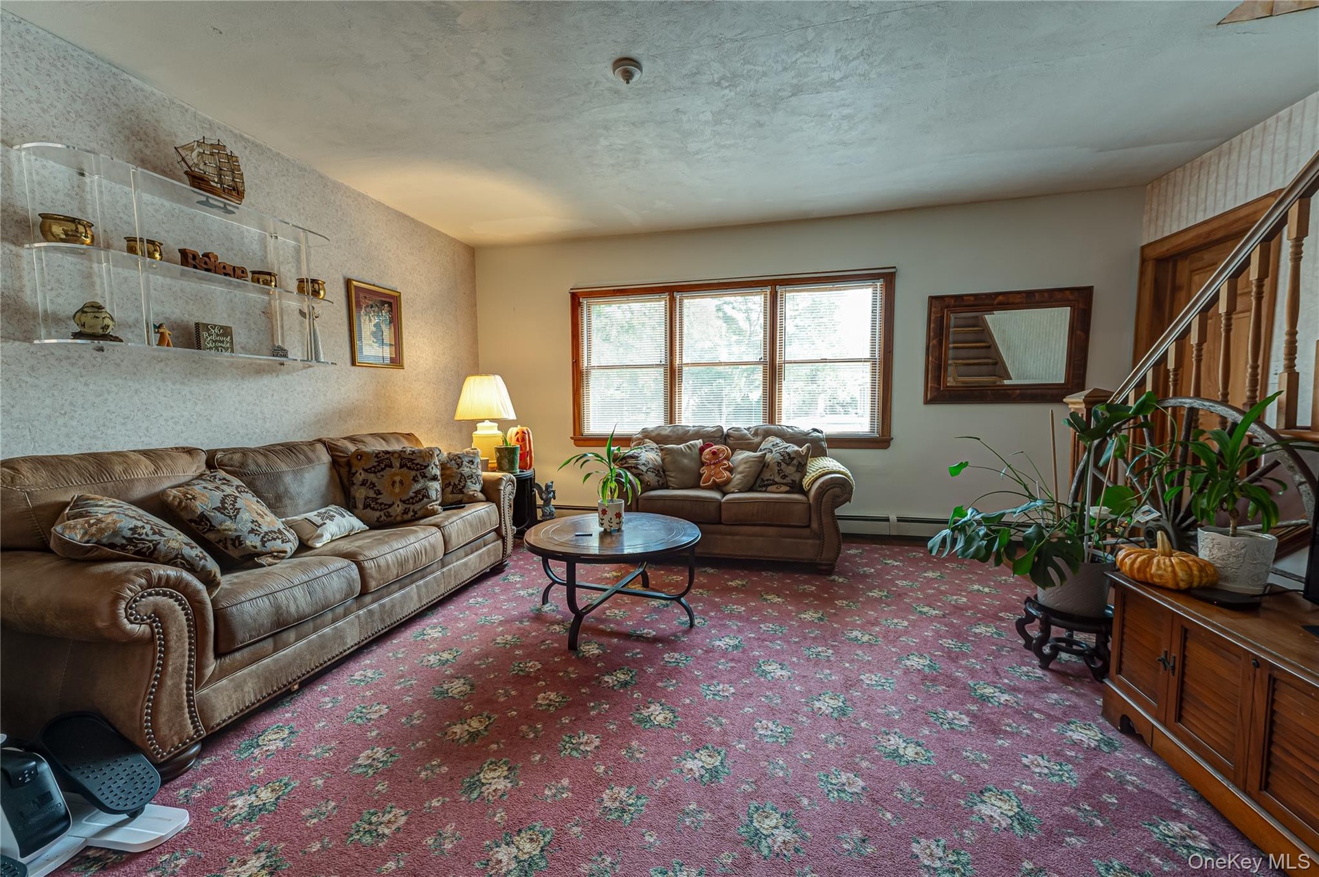 Sun-filled Living area featuring a large window, a wooden staircase with decorative balusters and hardwood floors.