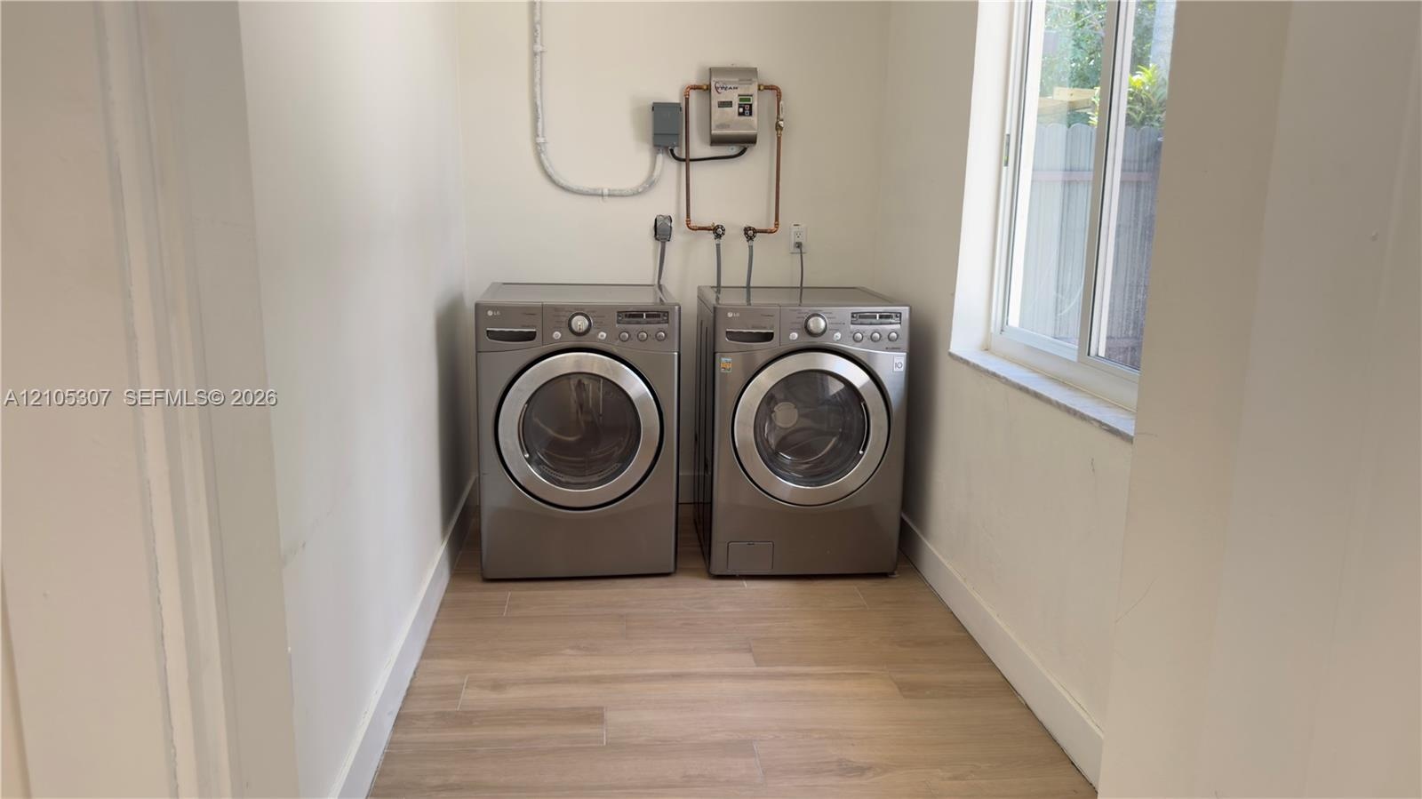 Dedicated laundry space featuring wood-finish flooring and a single-hung window