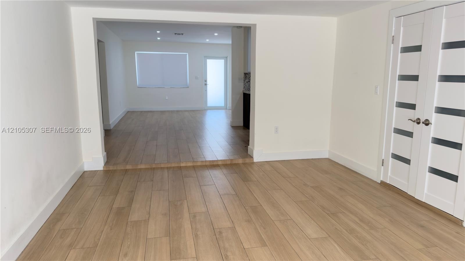 Wood-finish flooring throughout, recessed ceiling lighting, and double-door entry featuring glass horizontal panels