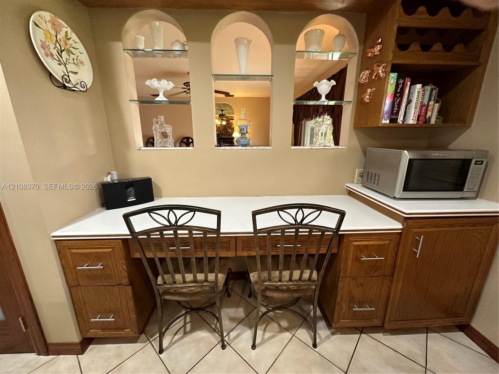 Built-in wood cabinetry featuring brushed nickel hardware, expansive solid-surface countertop, three arched display niches with glass shelving, and in