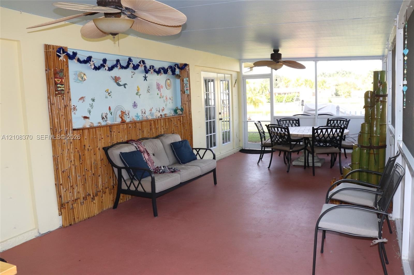 Screened-in lanai featuring a solid-surface floor, dual ceiling fans, and bamboo-accented wall detailing