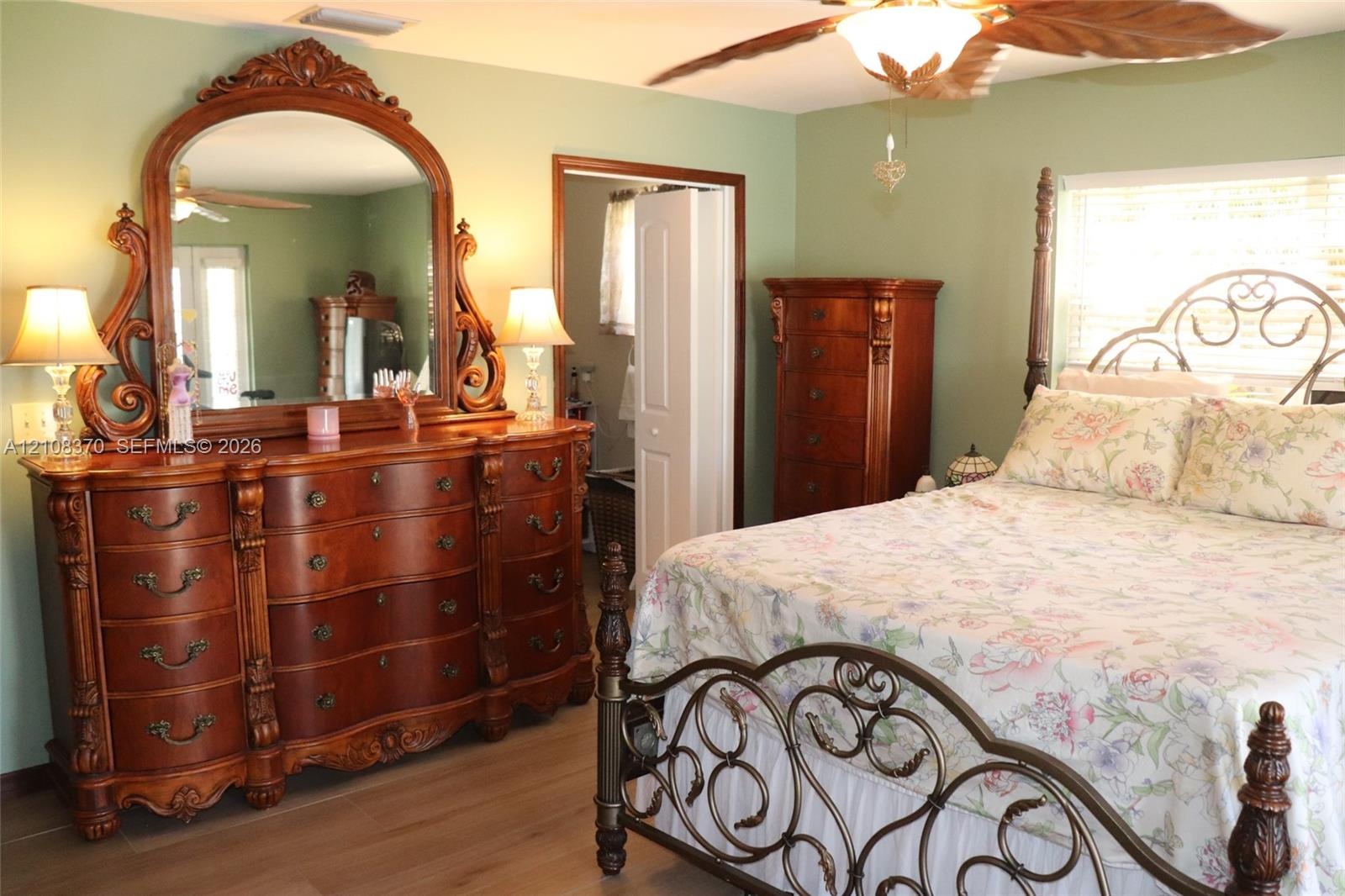 Room featuring wood-finish flooring, a ceiling fan, and louvered closet doors