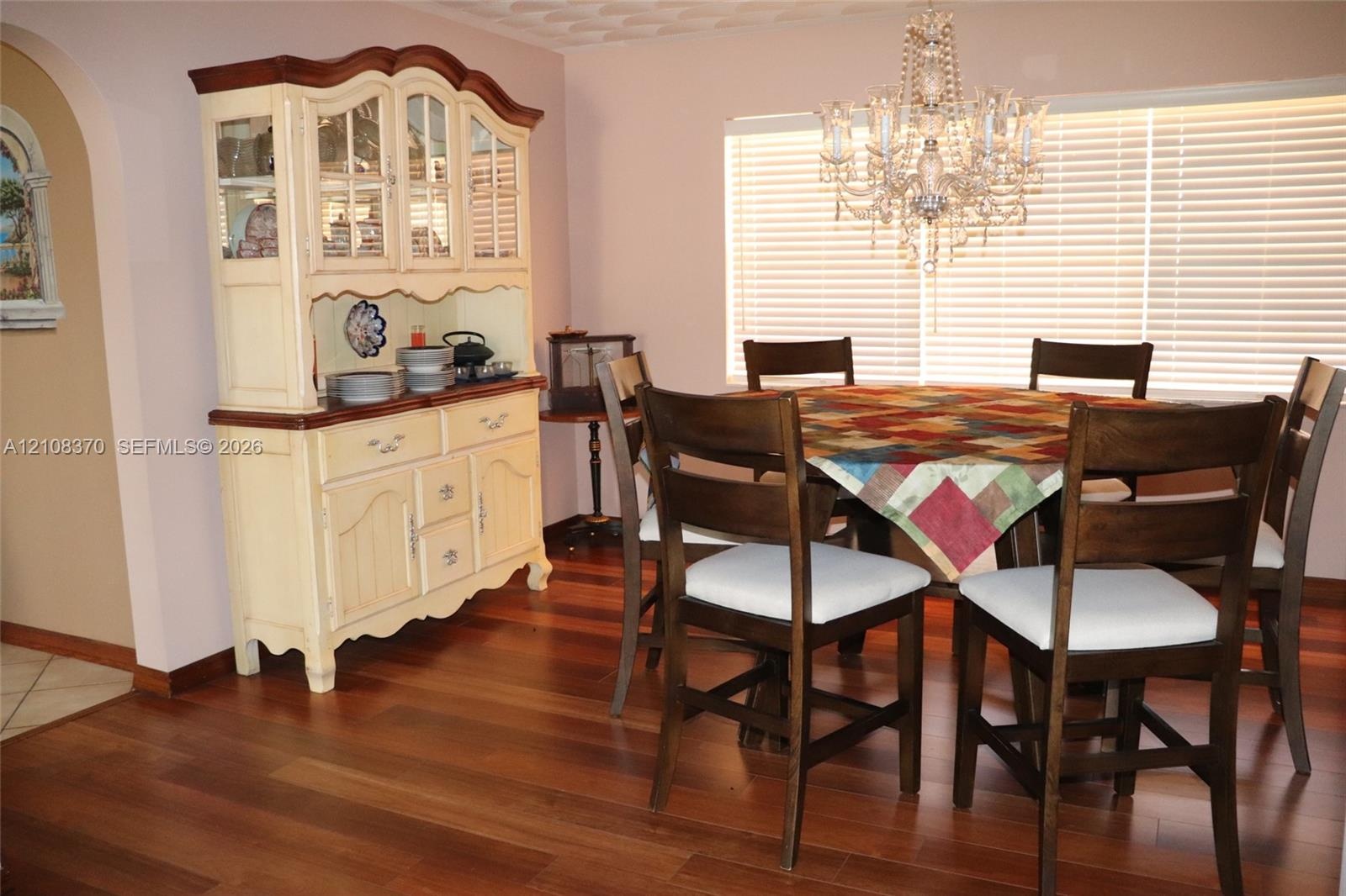 Wood-finish flooring, crystal-style chandelier, and an arched wall opening