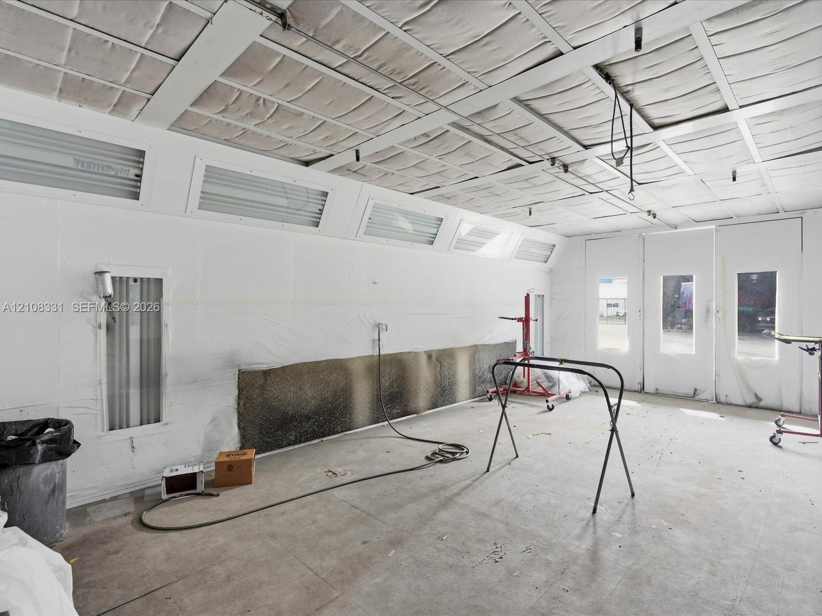 Industrial spray booth featuring insulated panel wall construction, integrated overhead lighting, dedicated air ventilation intake ports, and dual gla