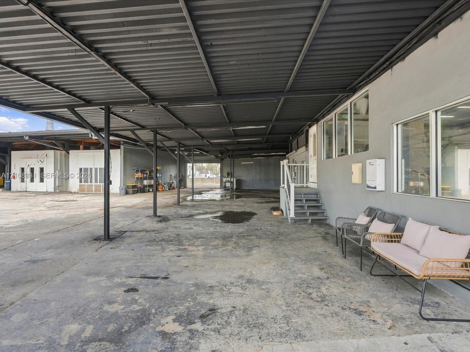 Expansive covered exterior area featuring a high-clearance metal roof canopy, concrete foundation, and multi-paned windows