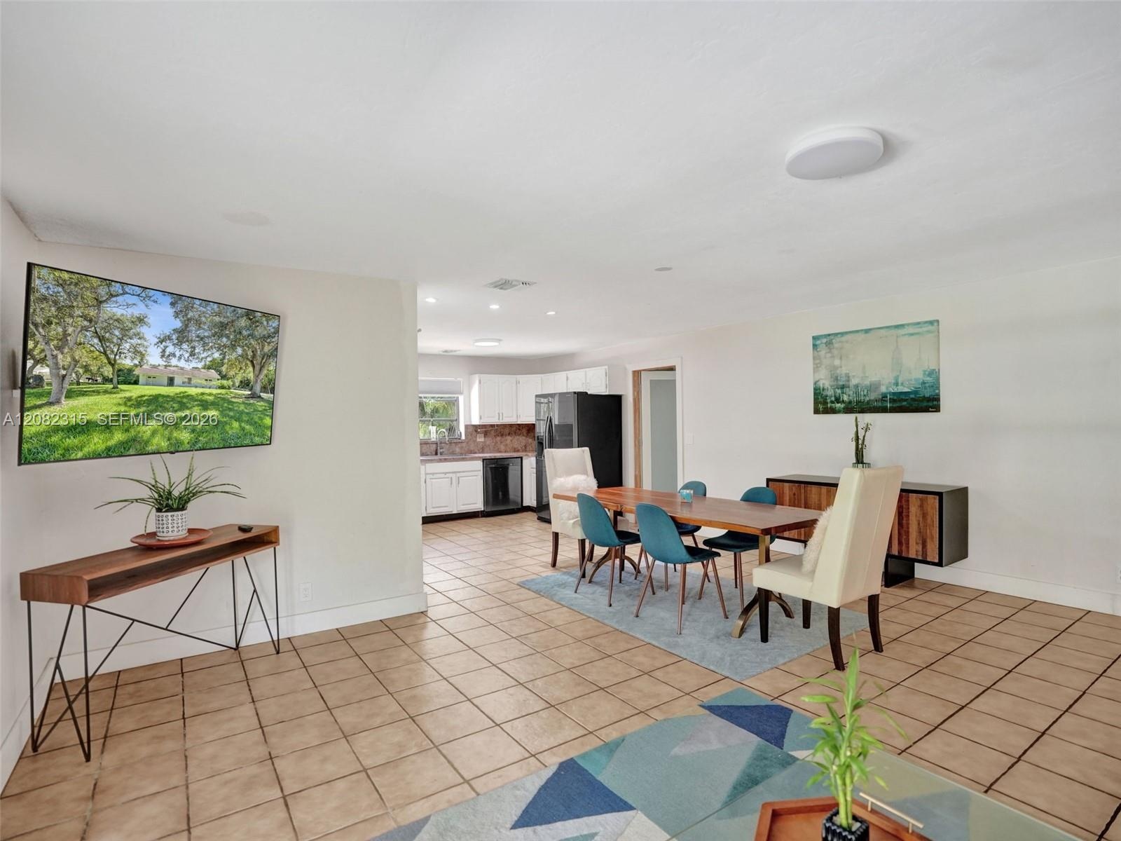 Open-concept interior featuring ceramic tile flooring, recessed lighting, and kitchen cabinetry with a neutral finish