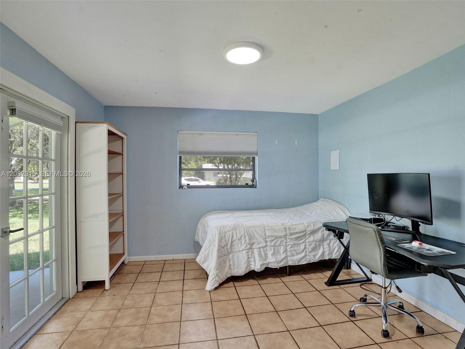 Room featuring tile flooring, a glass-paned door, a single-hung window with a roller shade, and a flush-mount overhead light fixture