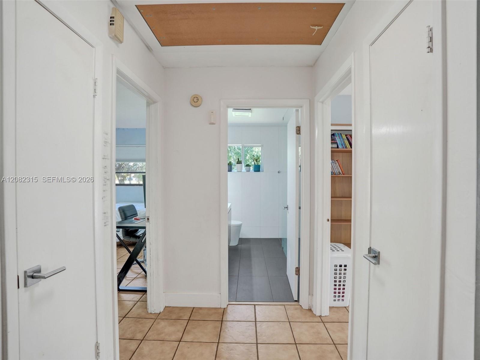 Ceramic tile flooring, white slab doors with modern lever hardware, and built-in shelving unit