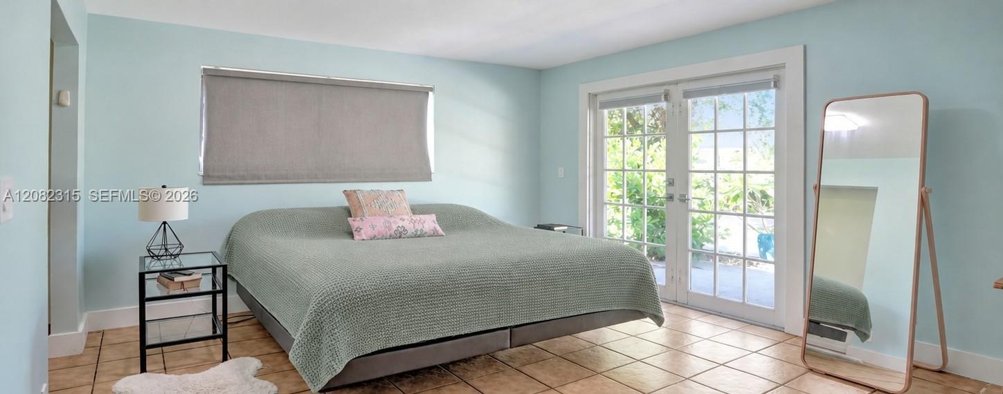 Room featuring ceramic tile flooring, multi-pane French doors, and a rectangular window with a roller shade