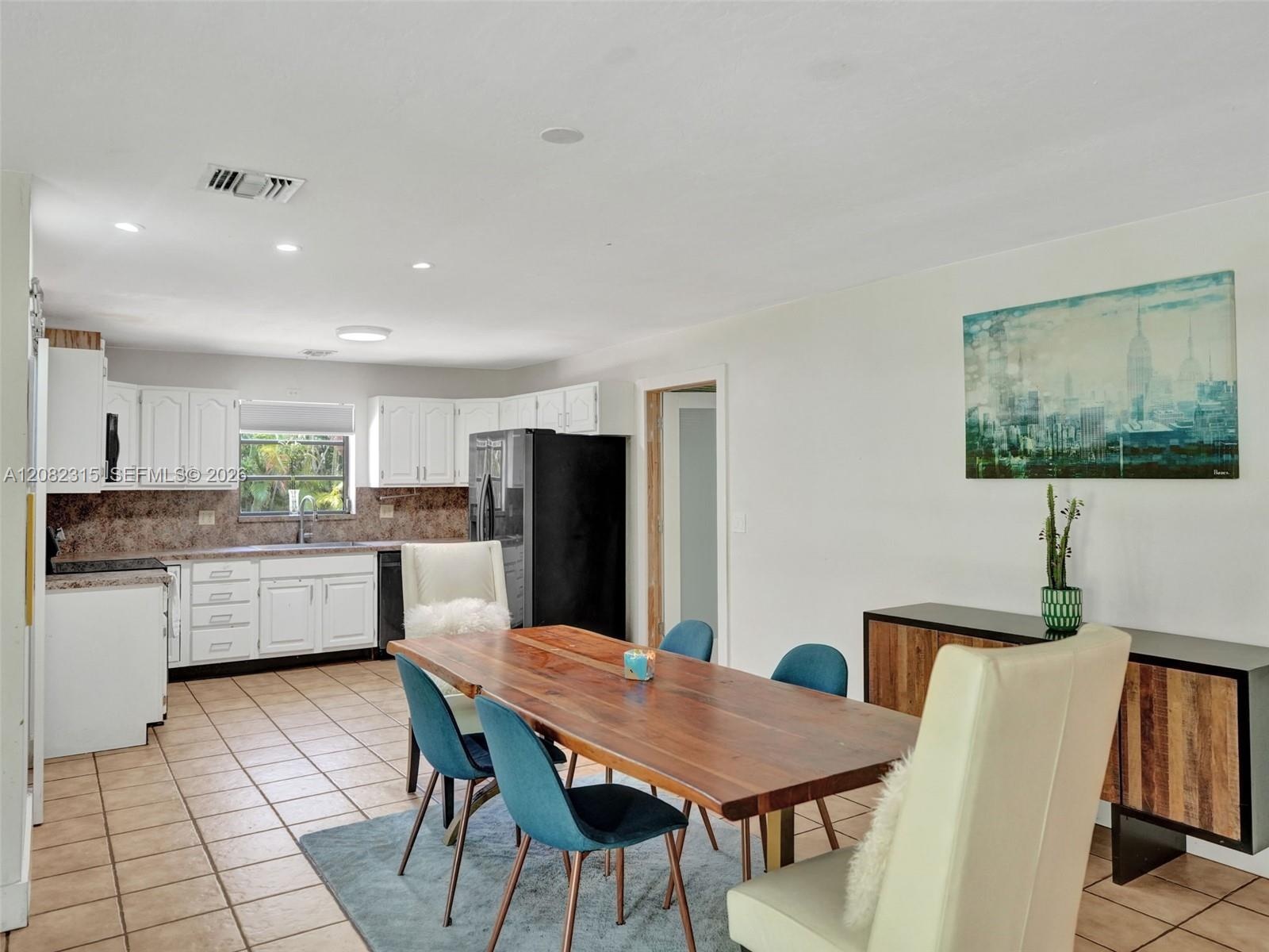 Kitchen featuring white shaker-style cabinetry, tiled flooring, recessed lighting, and a window over the stainless steel sink