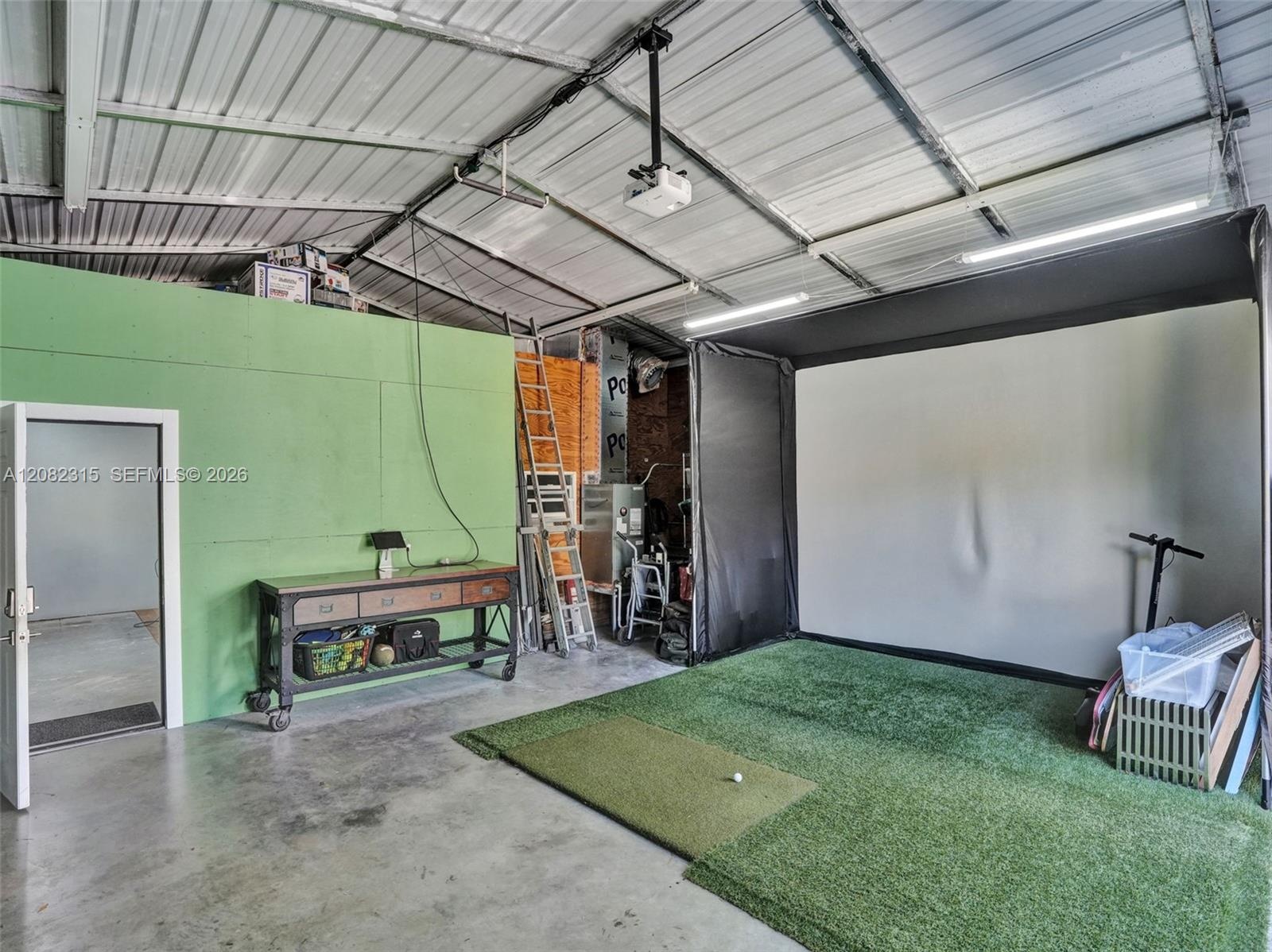 Garage space featuring a vaulted ceiling with exposed metal structural elements, concrete flooring, and linear LED lighting