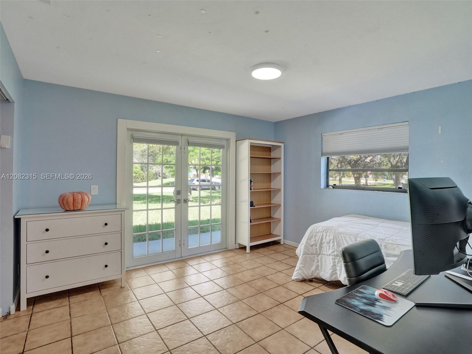 Room featuring tile flooring, glass-paneled double doors, and a built-in recessed shelving unit