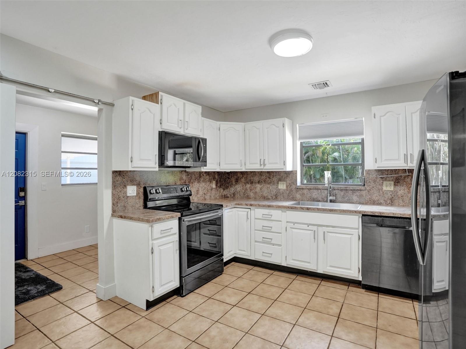 Kitchen featuring white cabinetry, stone-finish countertops, tiled flooring, and stainless steel appliances