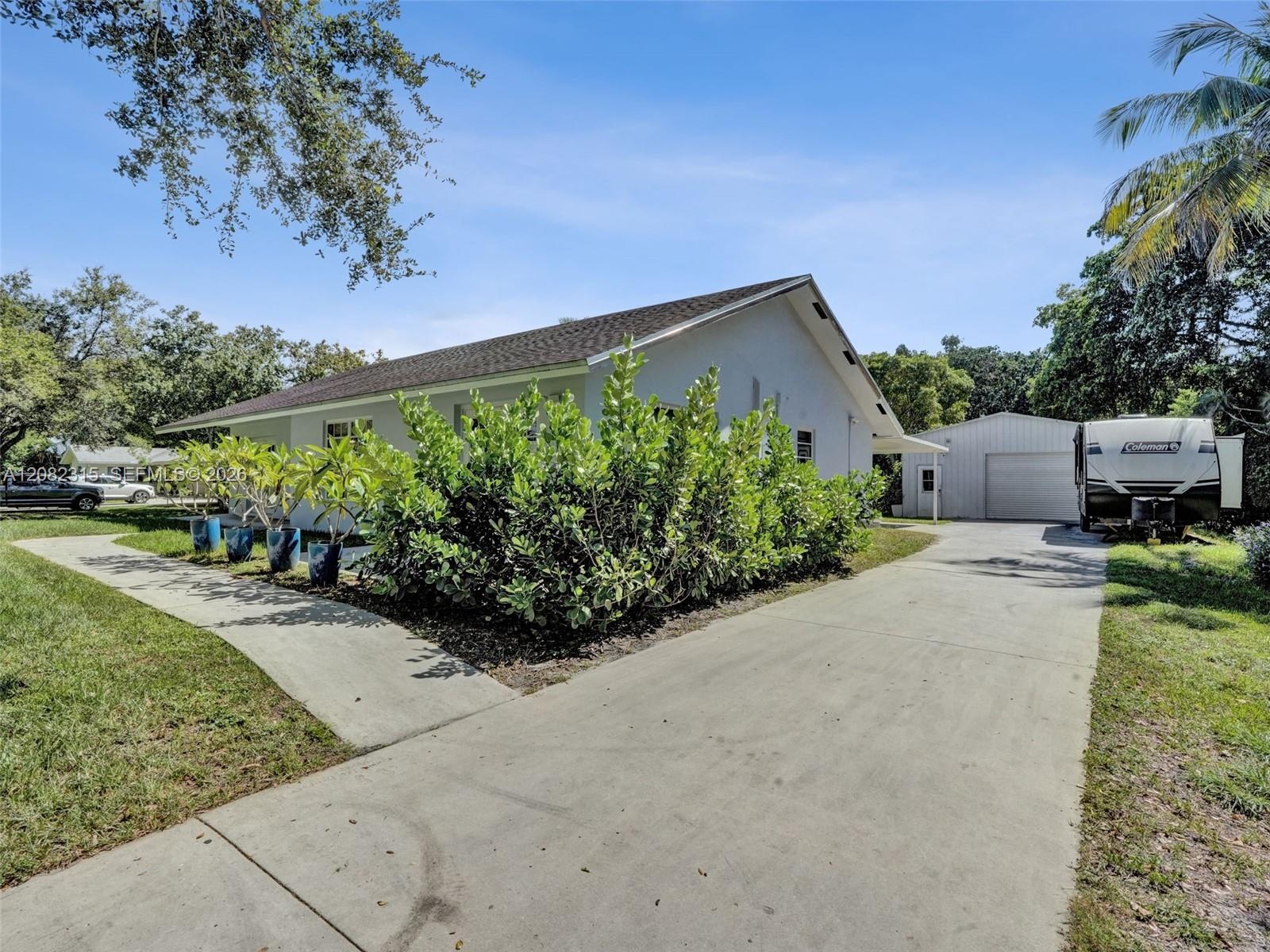 Single-story residence featuring a concrete driveway, detached garage with metal siding, and a paved walkway leading to the entrance
