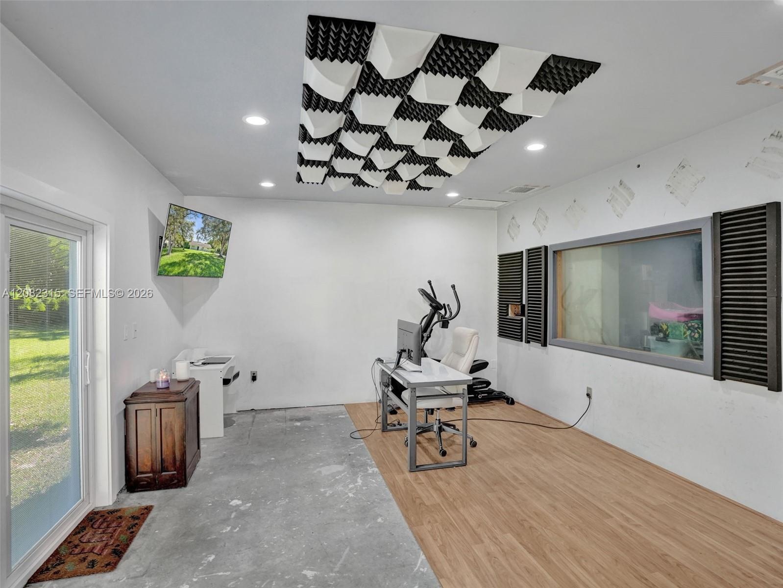 Ceiling-mounted acoustic soundproofing panels, recessed lighting, wood-finish flooring, glass-paneled interior window, and full-light exterior door
