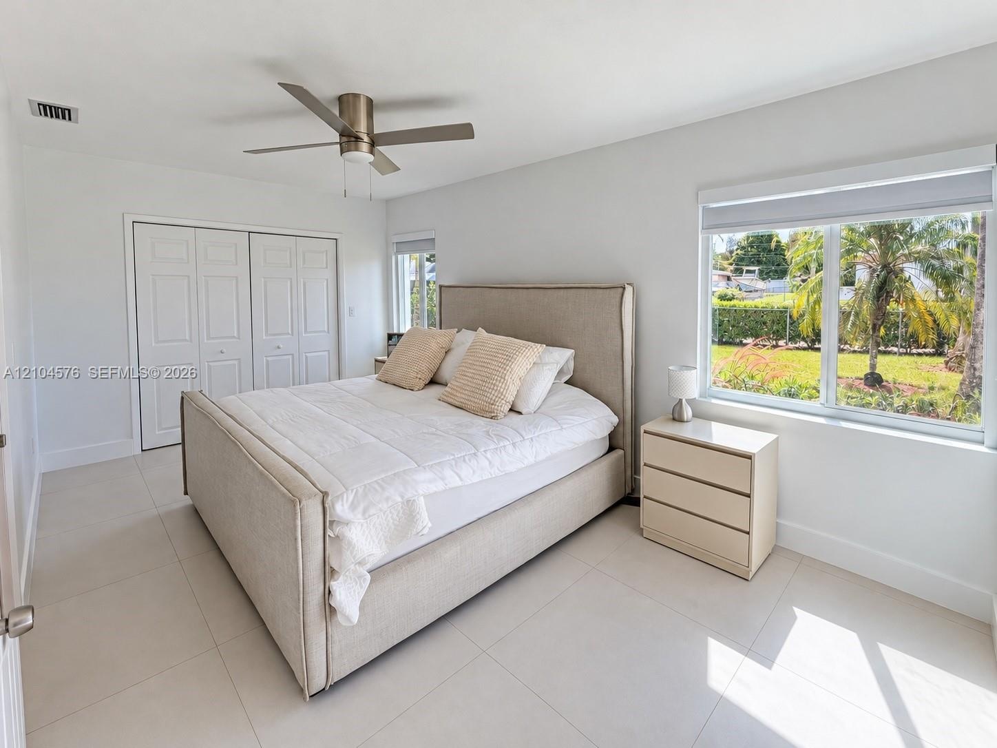 High-gloss white cabinetry, stainless steel French-door refrigerator, stone-surface countertop, recessed ceiling lighting, and large-format tile floor
