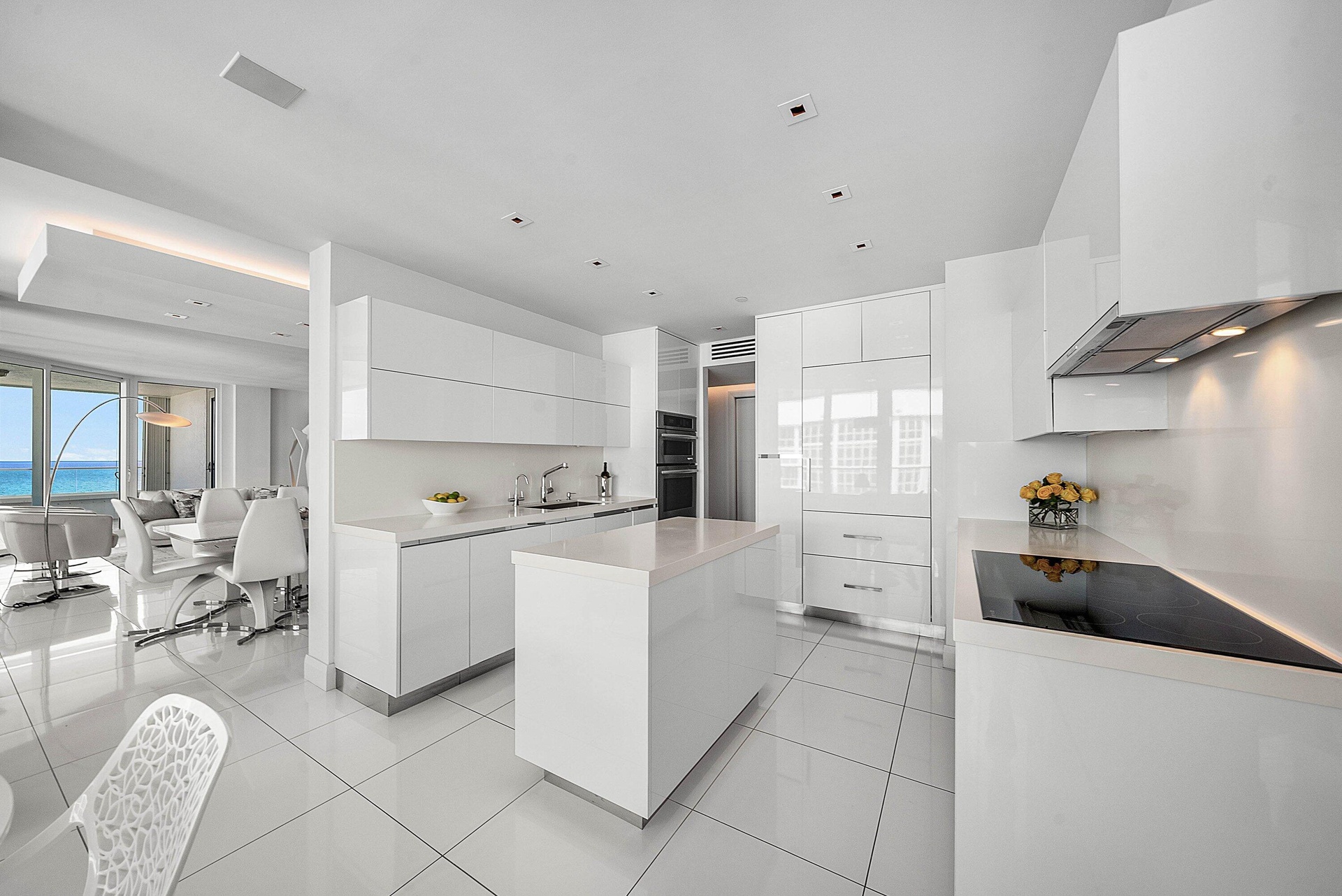 Modern kitchen featuring high-gloss cabinetry, stone countertops, integrated appliances, a central island, and large-format tile flooring