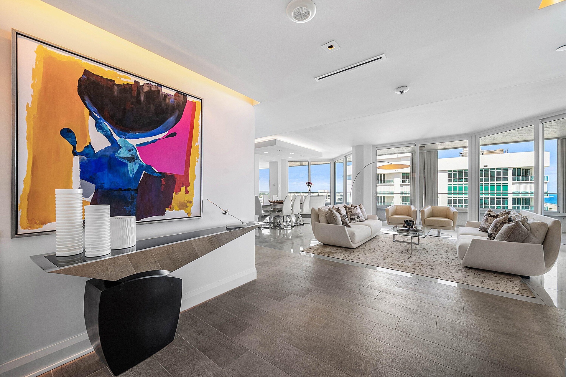 Floor-to-ceiling windows, wood-finish tile flooring, recessed ceiling lighting, and custom wall-mounted entryway console