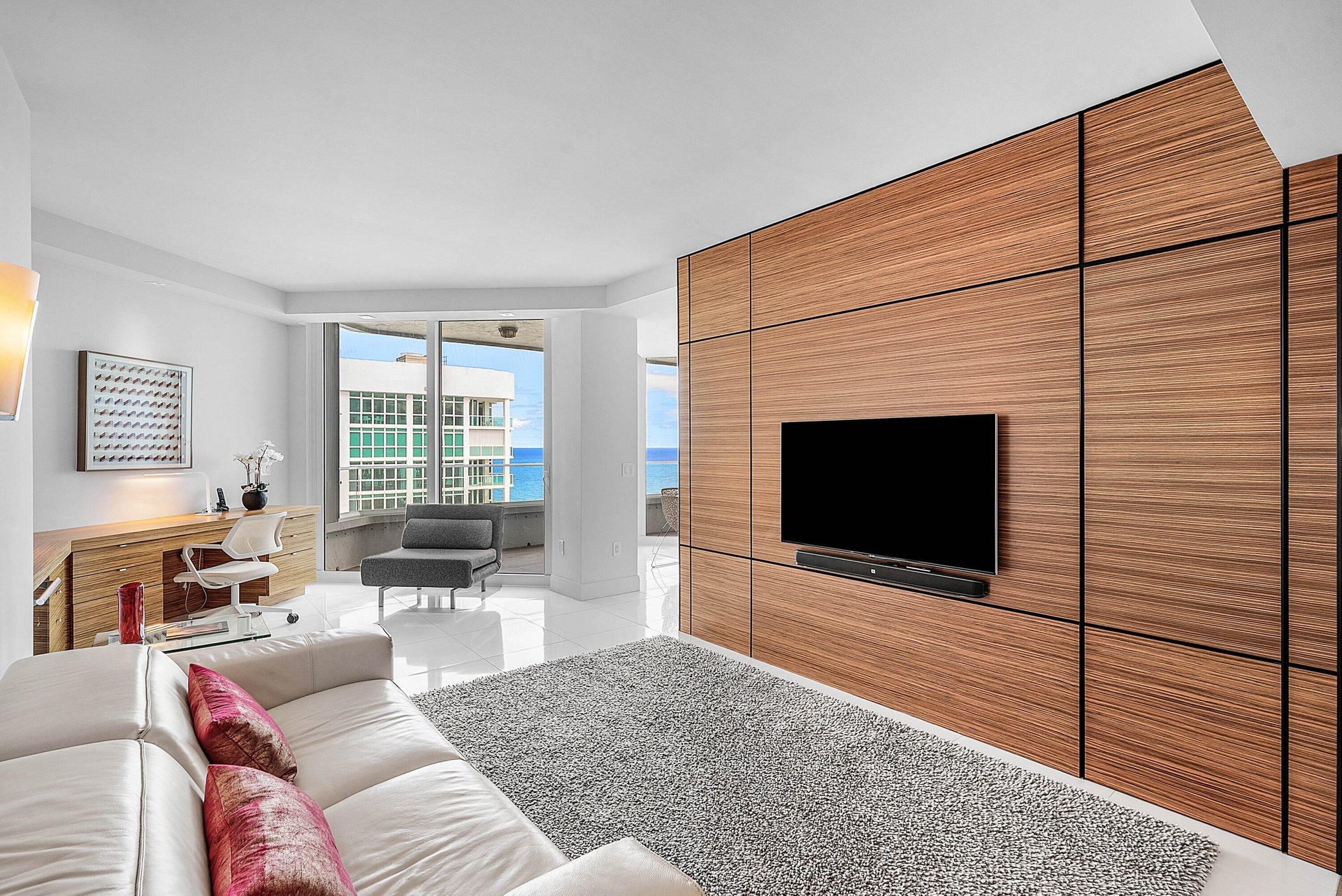Floor-to-ceiling wood-panel accent wall, built-in desk cabinetry, floor-to-ceiling glass windows, and polished tile flooring