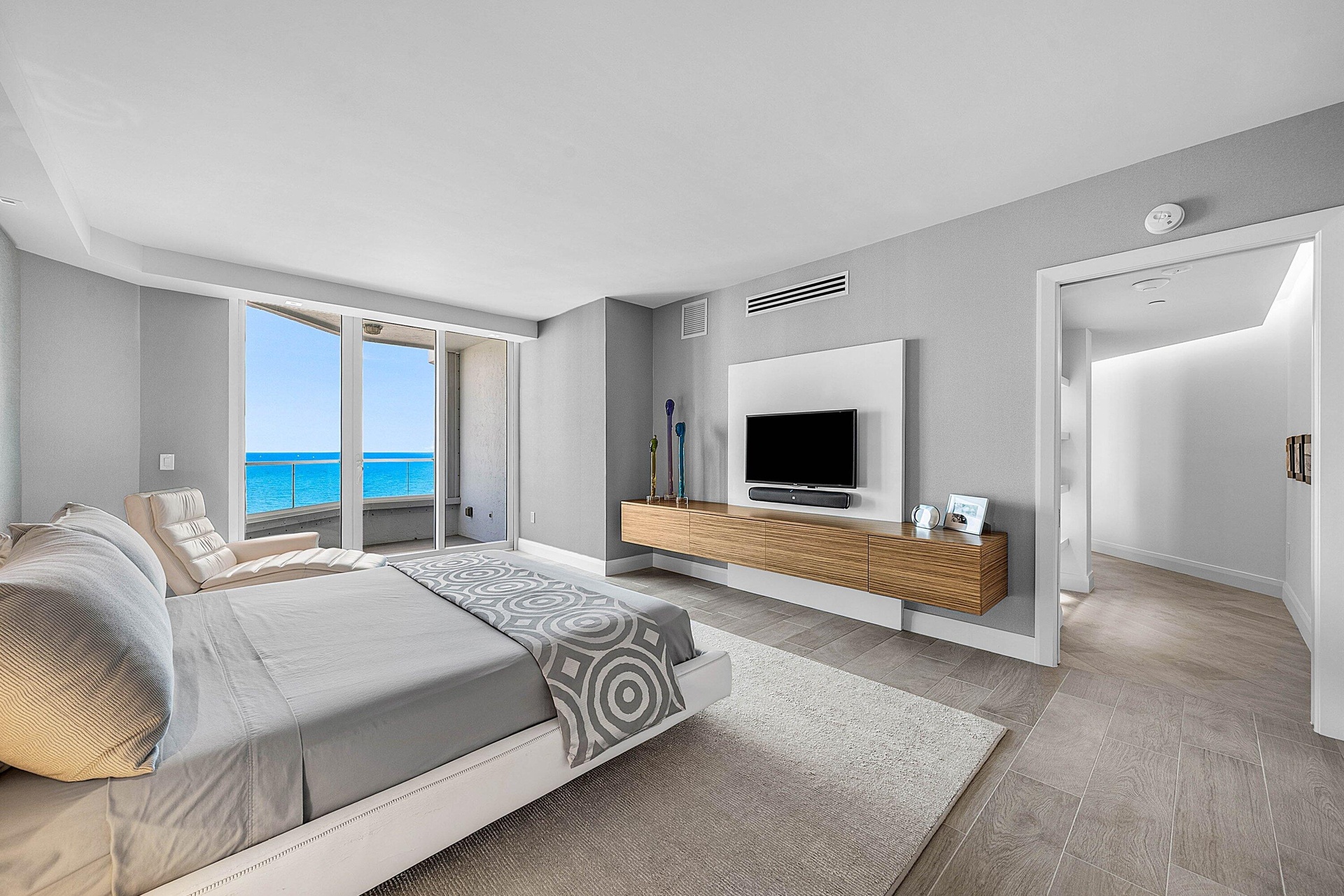 Floor-to-ceiling glass sliding doors, wood-finish flooring, floating wood-veneer media console, and built-in wall-mounted paneling