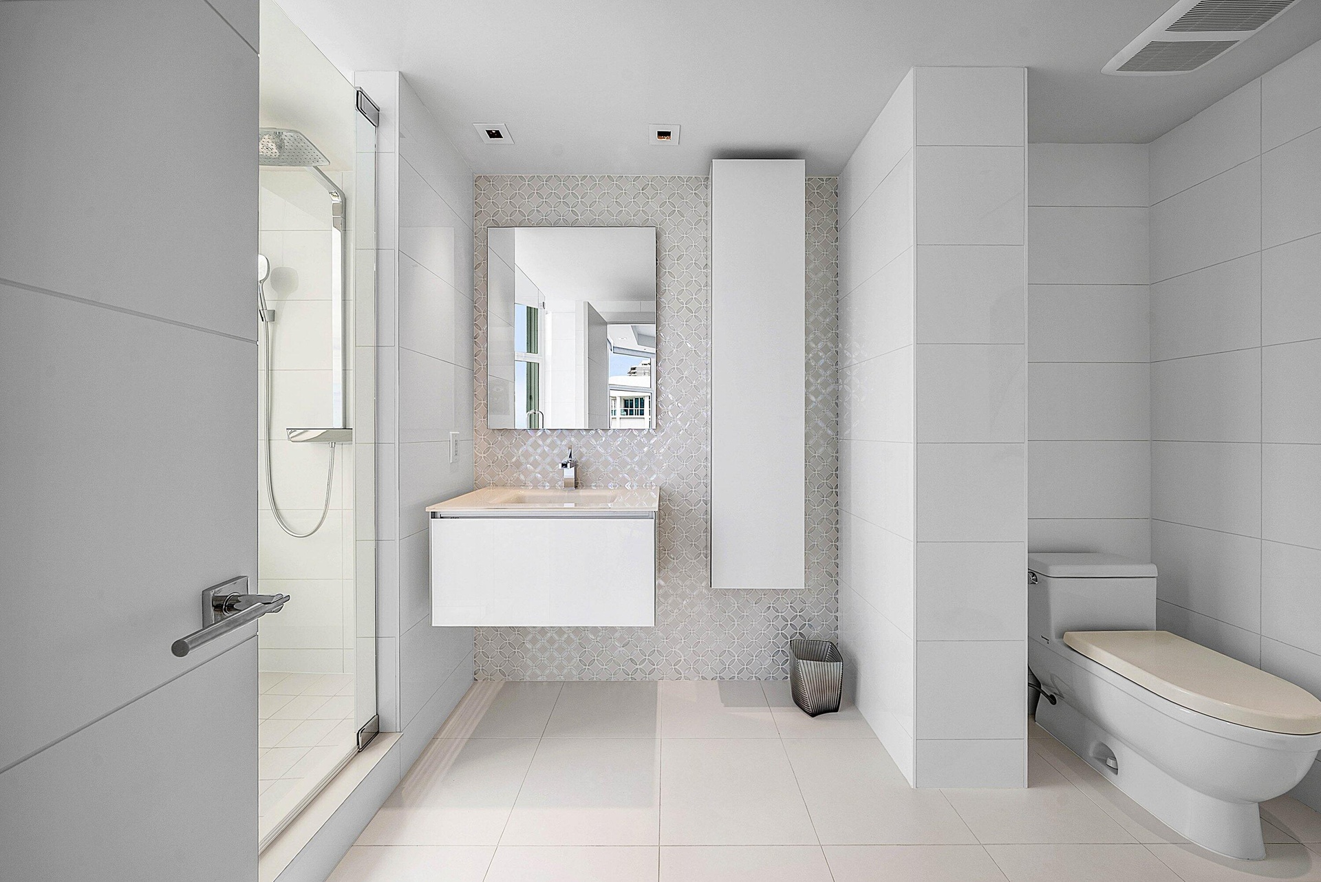 Modern bathroom featuring a glass-enclosed shower, wall-mounted floating vanity, integrated rectangular sink, full-height decorative tile backsplash, 