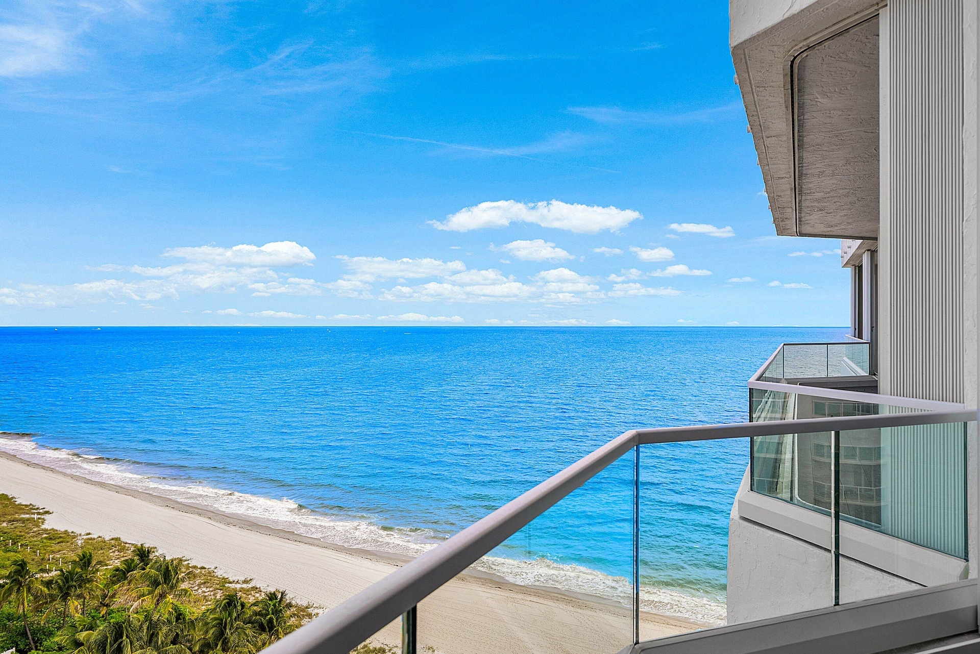 Private balcony featuring glass railings and direct oceanfront positioning