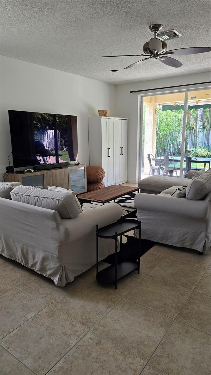 Large-format tile flooring, ceiling fan with integrated lighting, and full-height sliding glass door