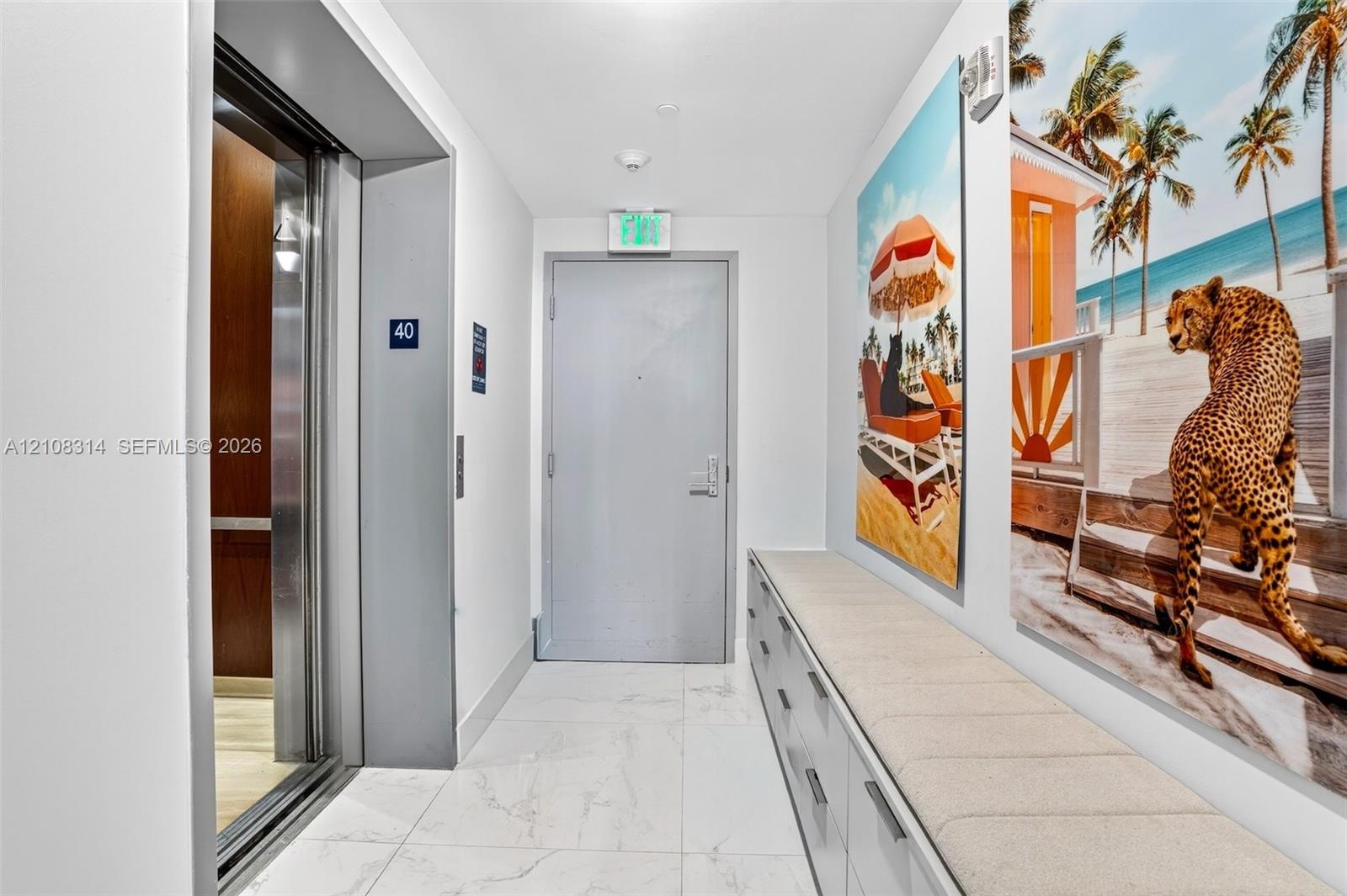 Elevator access featuring metallic sliding doors, white large-format stone-look floor tiles, and custom built-in cabinetry with a stone countertop