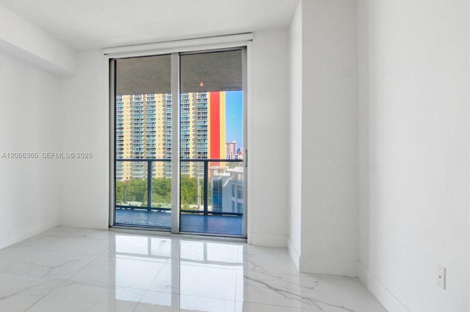 Large-format white tile flooring, floor-to-ceiling glass sliding doors, and a metal-railed exterior balcony