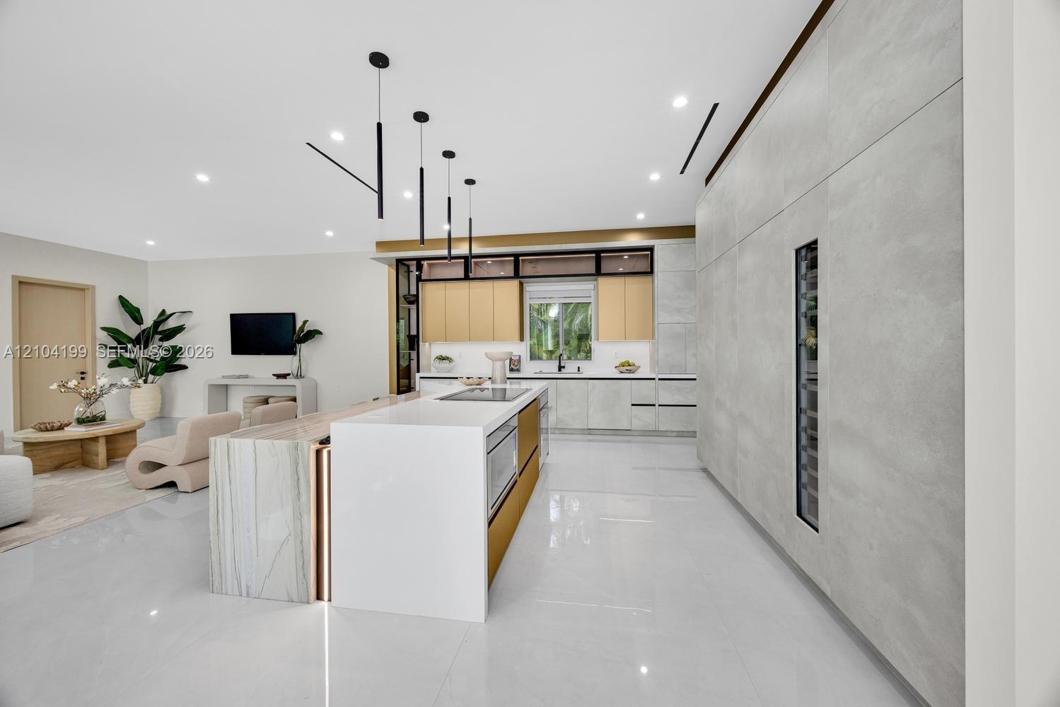 Kitchen featuring a central island with waterfall-edge countertop, floor-to-ceiling cabinetry with integrated beverage storage, matte metallic base ac