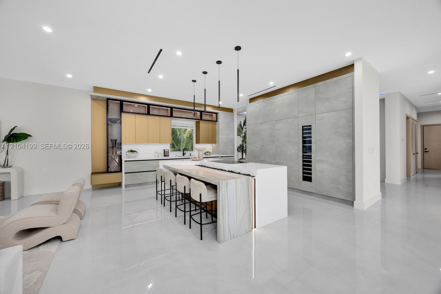 Custom kitchen featuring a stone-topped waterfall island, full-height cabinetry with integrated refrigeration, metallic-tone upper accent cabinets, an