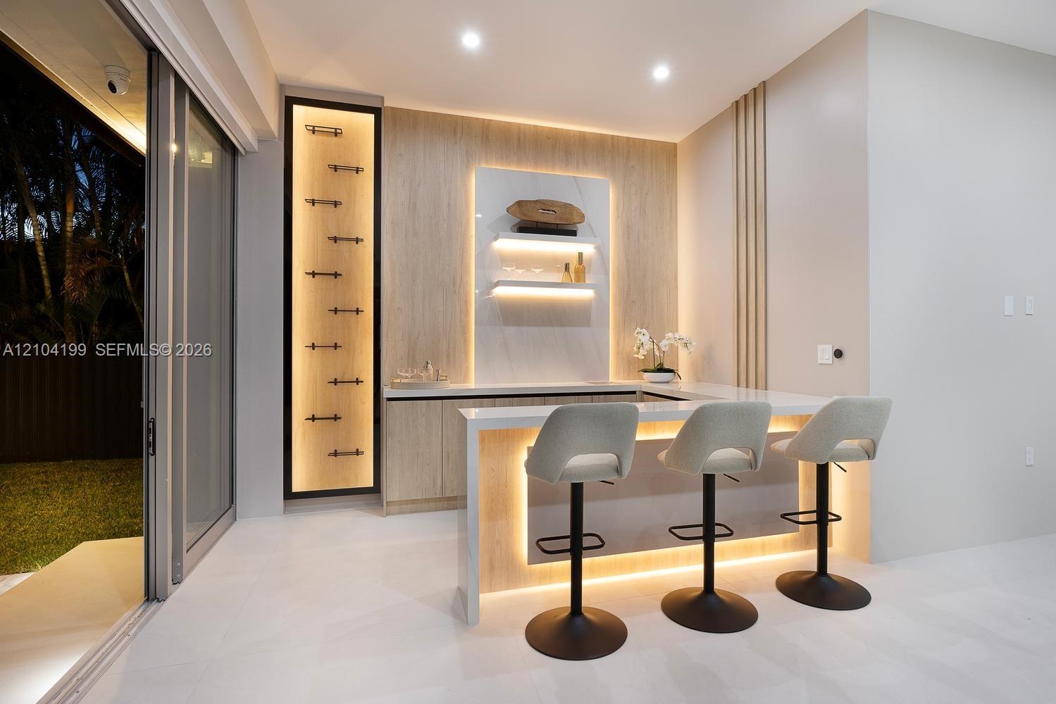 Built-in bar featuring wood-finish cabinetry, stone-surfaced countertop, vertical accent paneling, integrated recessed shelving, and under-counter lig