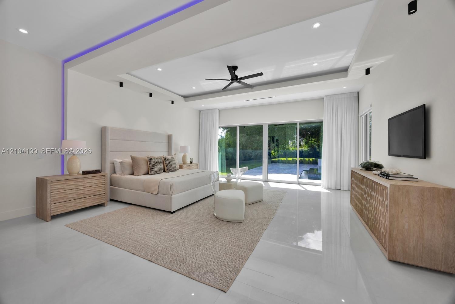 Tray ceiling featuring integrated LED lighting, polished tile flooring, recessed lighting, ceiling fan, and floor-to-ceiling sliding glass doors