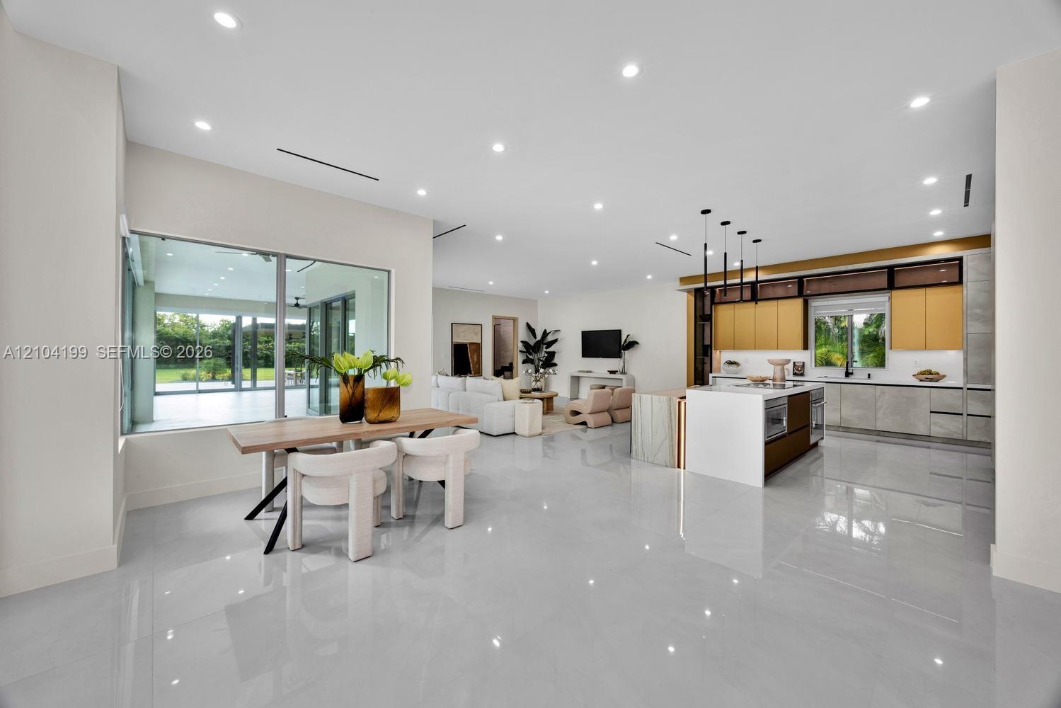 Open-concept interior featuring large-format tile flooring, recessed lighting, and a kitchen equipped with a central island and contemporary flat-pane