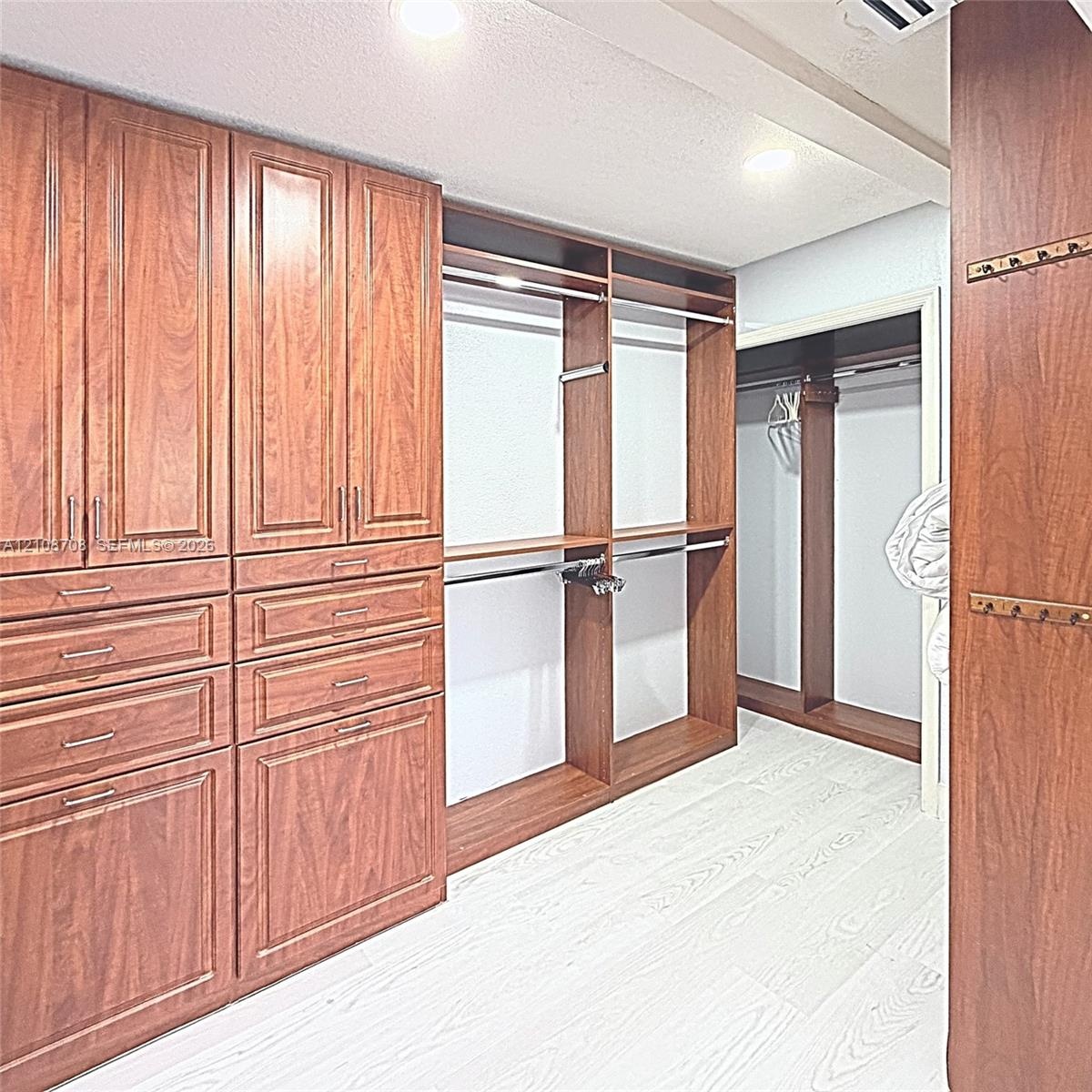 Custom wood-finish cabinetry featuring integrated drawers, shelving, hanging rods, and built-in metal hardware
