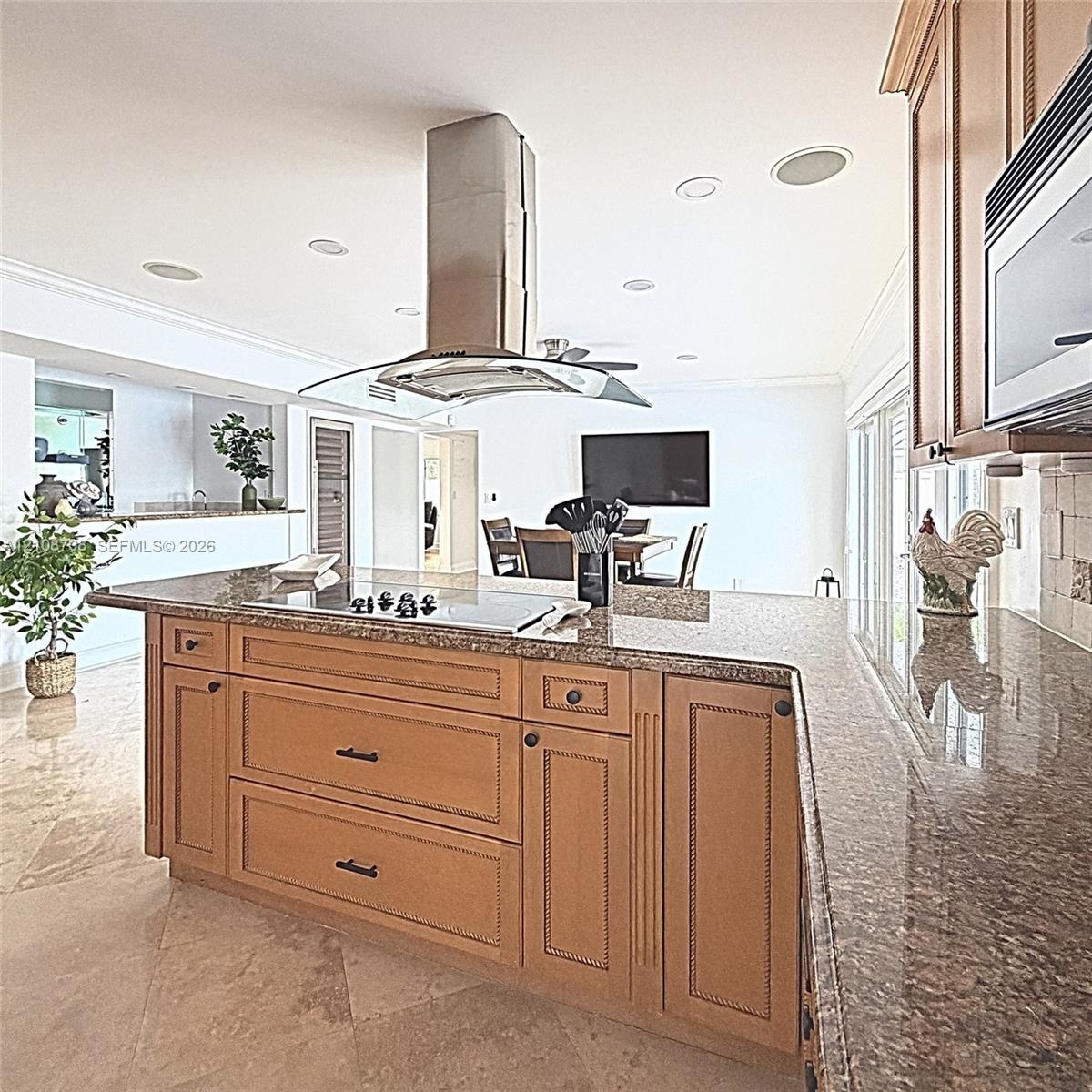 Kitchen island featuring stone countertops, integrated cooktop, stainless steel ceiling-mounted range hood, recessed lighting, and tile flooring