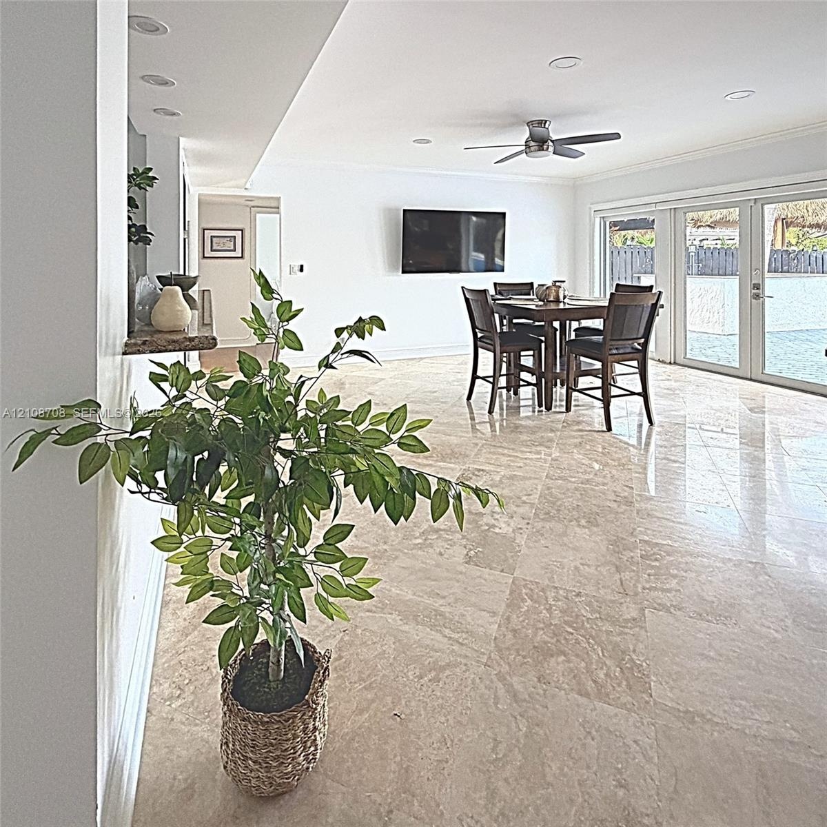 Large-format stone tile flooring, recessed ceiling lighting, ceiling fan, and sliding glass doors