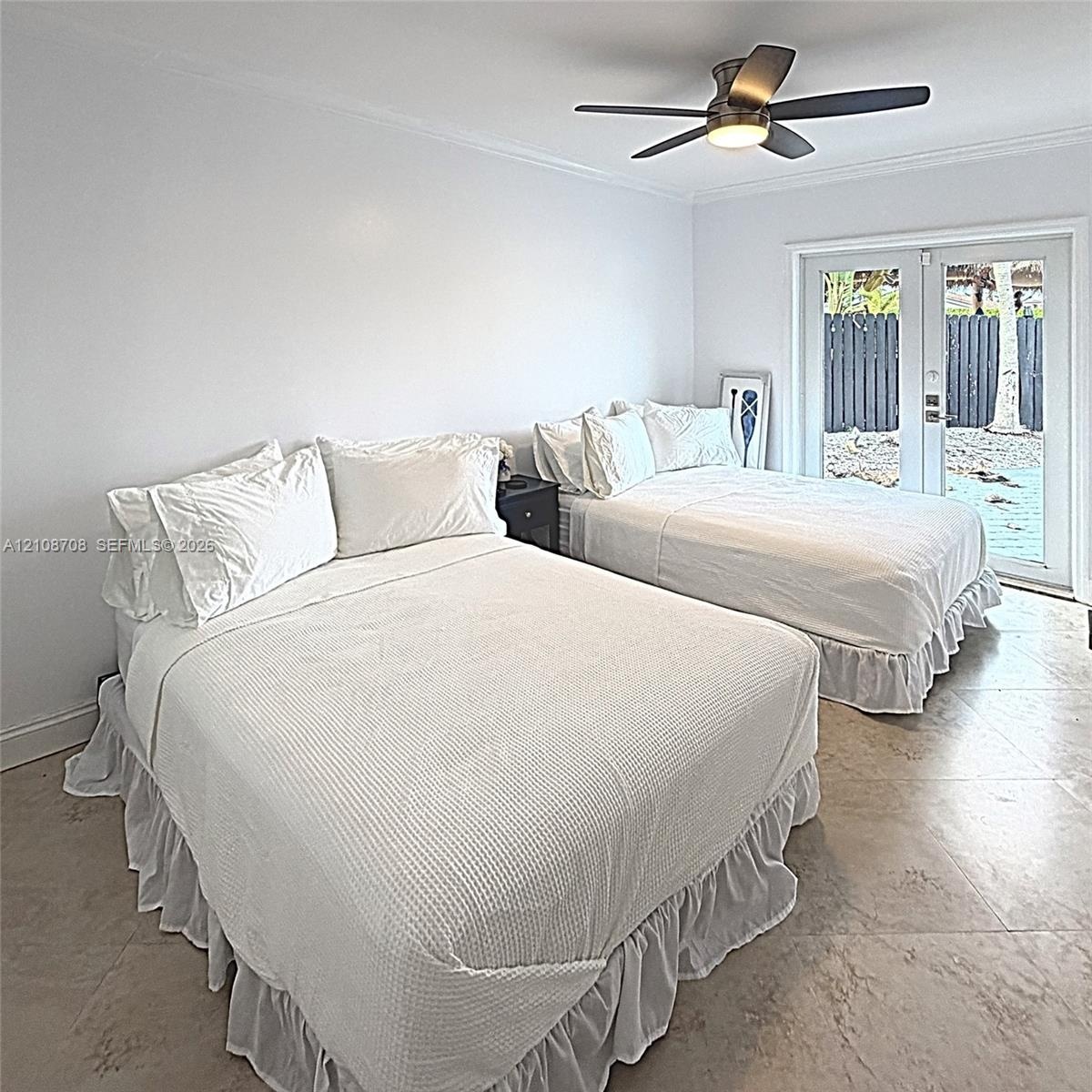 Large-format tile flooring, multi-pane glass french doors, and a ceiling-mounted light fixture with a five-blade fan