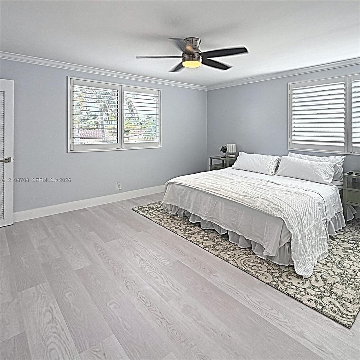 Wood-finish flooring, crown molding, plantation shutters, and a multi-blade ceiling fan with integrated lighting