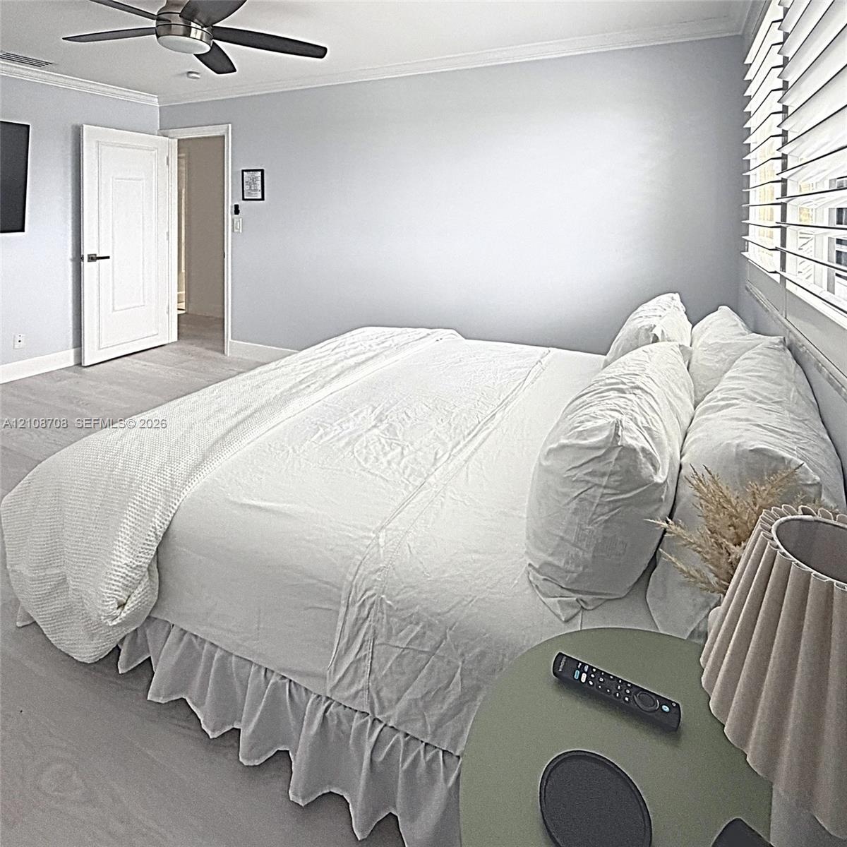 Neutral-toned room featuring wood-finish flooring, crown molding, a multi-blade ceiling fan, and horizontal window blinds