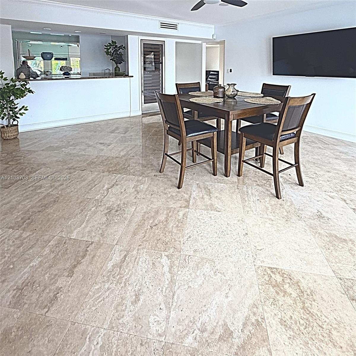 Open-concept floor plan featuring large-format stone flooring, a pass-through service counter, and a ceiling-mounted fan