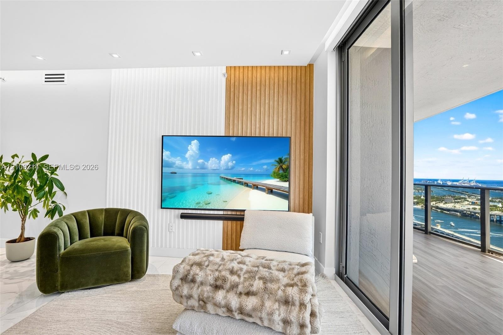 Custom accent wall featuring vertical wood-slat and fluted detailing, recessed ceiling lighting, and expansive floor-to-ceiling sliding glass doors le