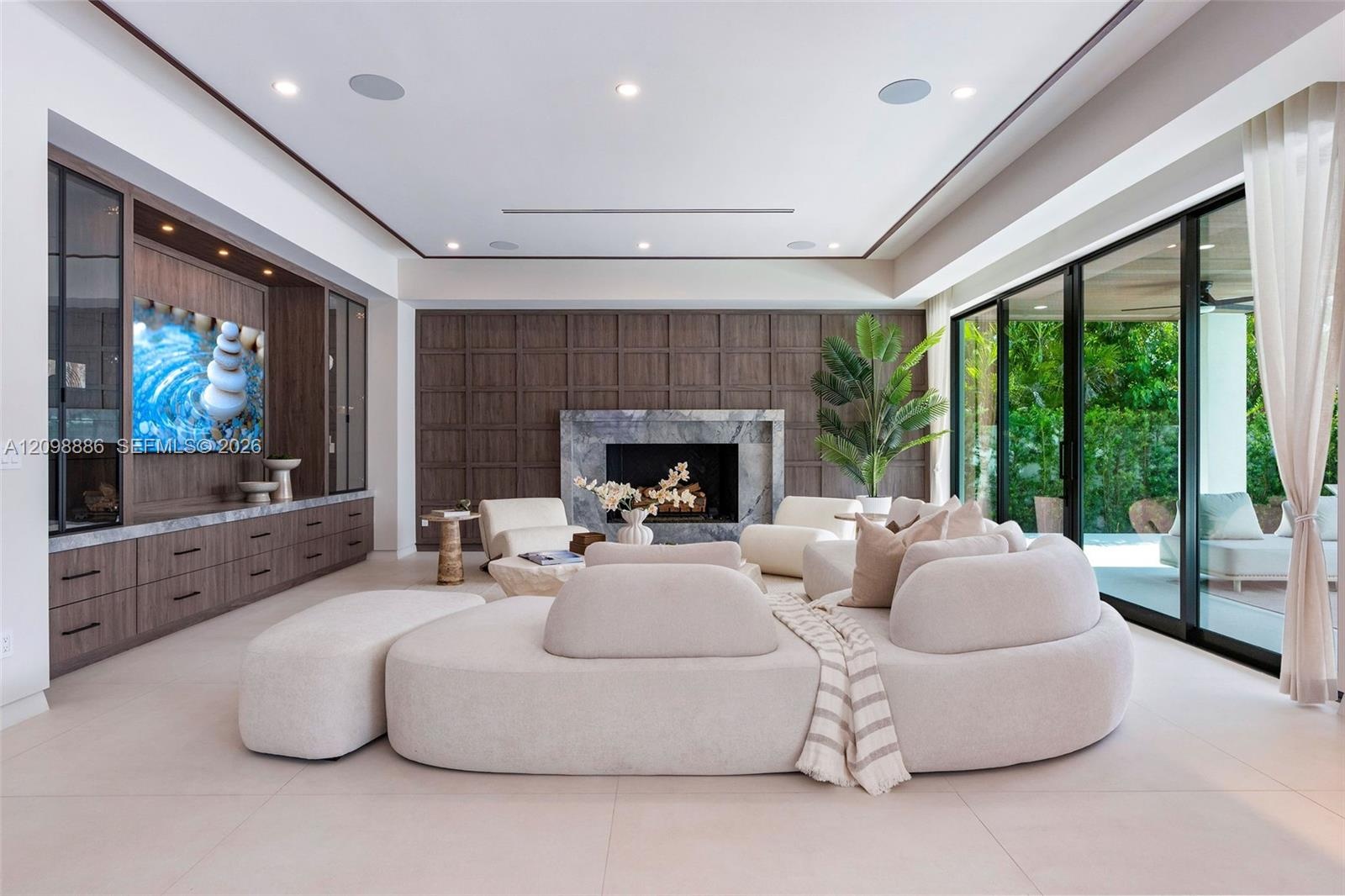 Living area featuring custom wood-finish built-in cabinetry, stone-surround fireplace, dark wood paneled accent wall, recessed ceiling lighting, and f
