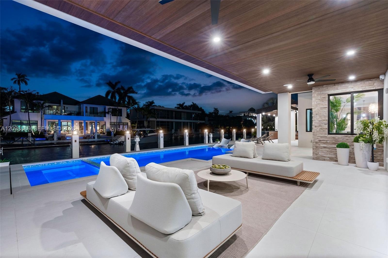 Covered outdoor living area featuring a wood-plank ceiling, recessed lighting, tile flooring, stone-veneer accent wall, and a rectangular swimming poo