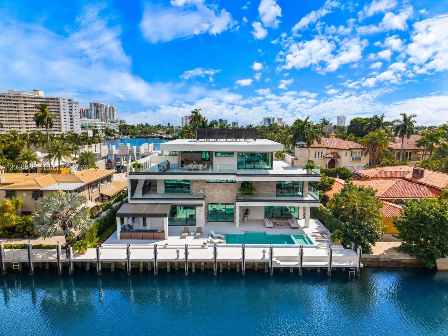 Modern waterfront residence featuring clean-lined architecture with multi-level design, expansive glass walls and sliding doors, open-air balconies wi